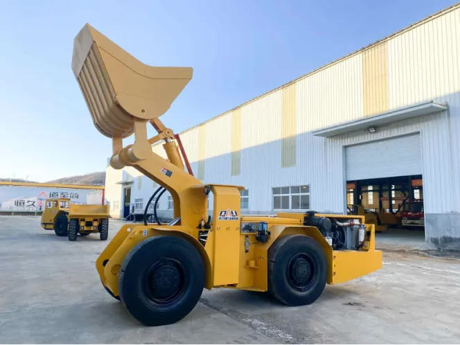 Compact diesel LHD underground loader with raised bucket positioned outside a mining equipment workshop